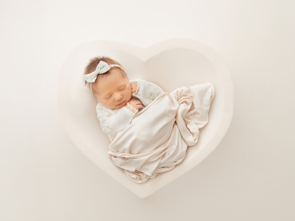 Sleeping newborn baby styled in soft neutral tones inside a heart-shaped setting for a timeless fine art newborn portrait near Tiptree, Essex.