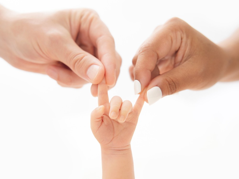 Tiny newborn hand holding both parents' fingers in a beautifully simple family detail portrait, photographed during an in-home newborn session near Kelvedon, Essex.