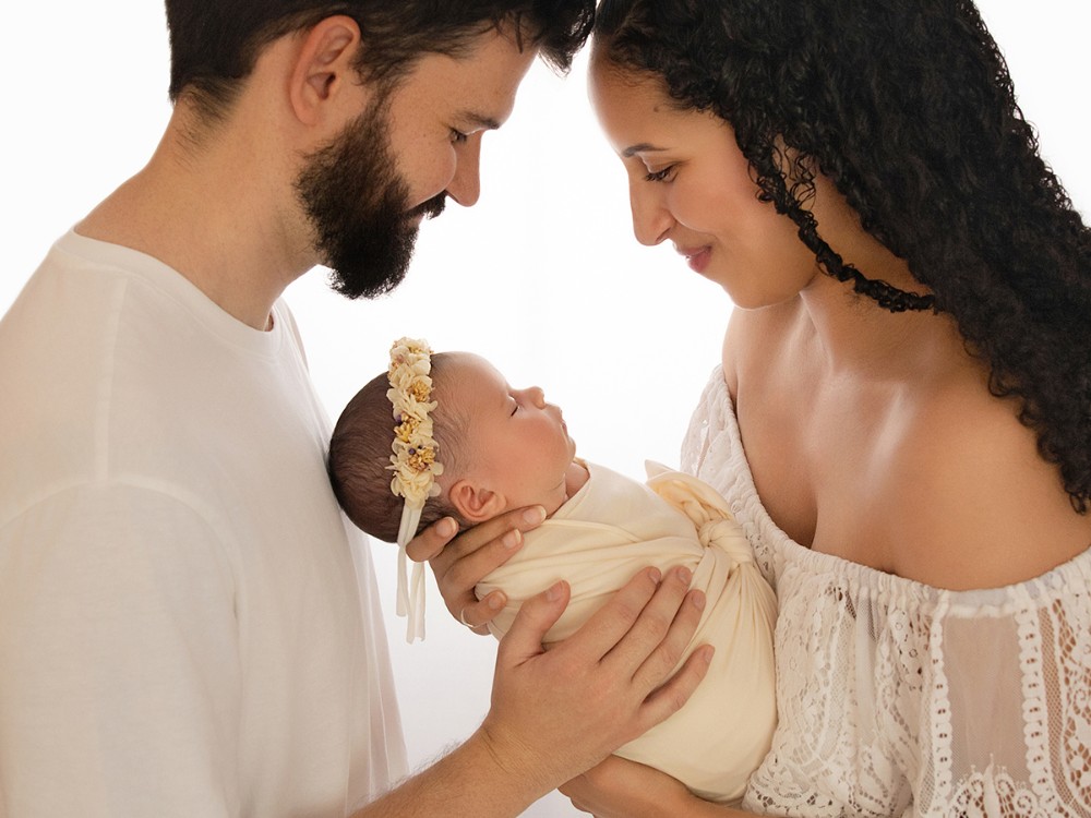 New parents lovingly holding their newborn baby during a relaxed in-home family and newborn photography session near Chelmsford, Essex.