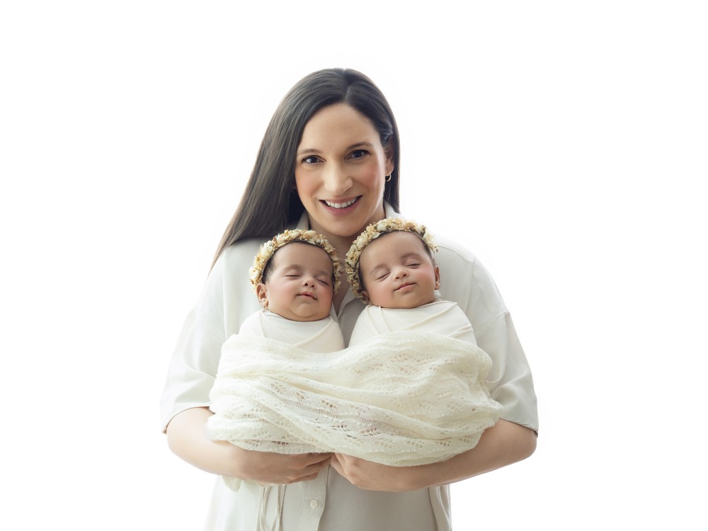 Mother holding her newborn twins during a light and timeless family portrait, created by an in-home newborn photographer serving Chelmsford, Essex.
