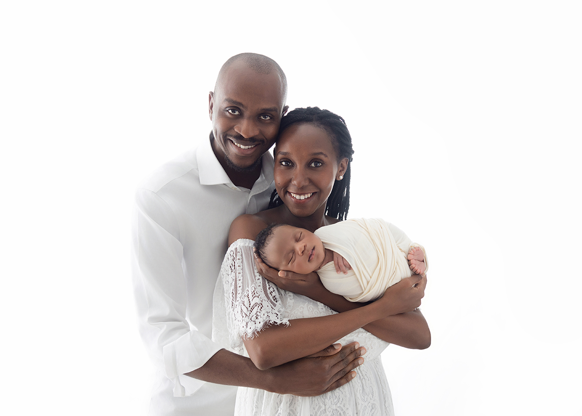Smiling parents holding their newborn baby together during a relaxed newborn photography session in Colchester Essex.