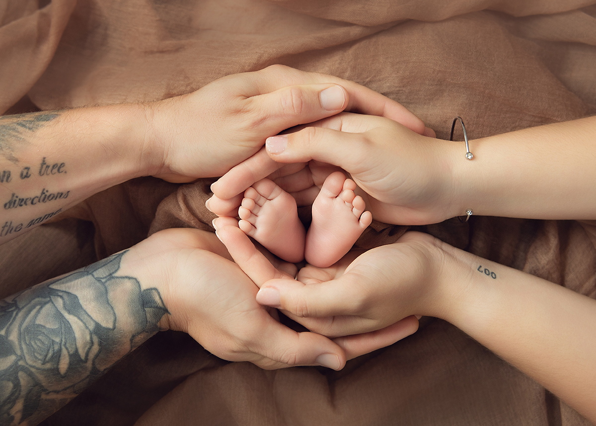 Tiny newborn baby feet gently held by both parents during a natural newborn photography session in Witham Essex.