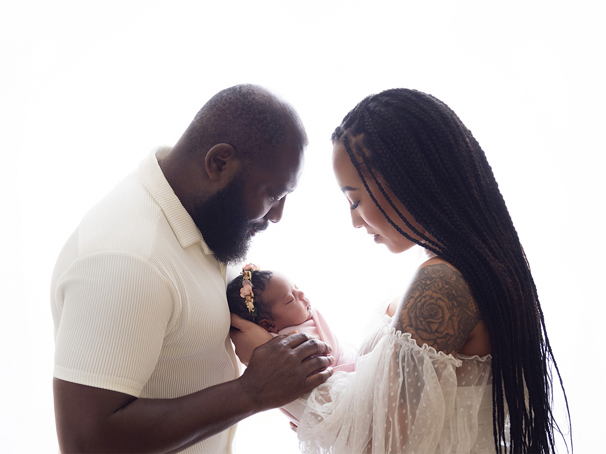 Parents wearing soft neutral clothing while admiring their newborn during an in-home family photography session in Essex.